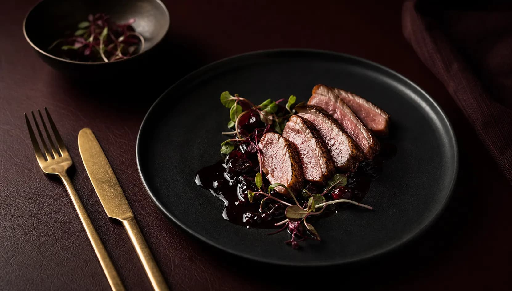 Smoked duck and dark cherry tasting course on black porcelain